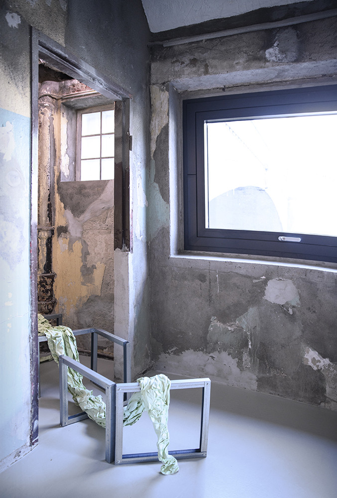 Raumansicht. Auf dem Boden steht ein Metallgerüst mit einem faltigen Tuch.