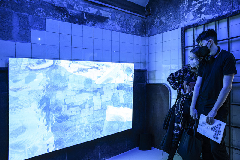 Besucher schauen sich Videokunst auf einem Fernseher an.