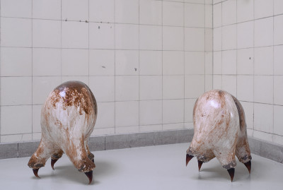 Alien skulptures stand on the floor. They are shaped like big chicken eggs, shiny white-brown and have pointed legs.