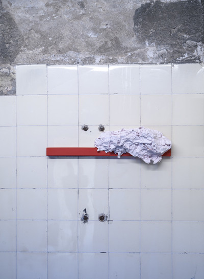 A wrinkled cloth hangs on a red bar on the wall.