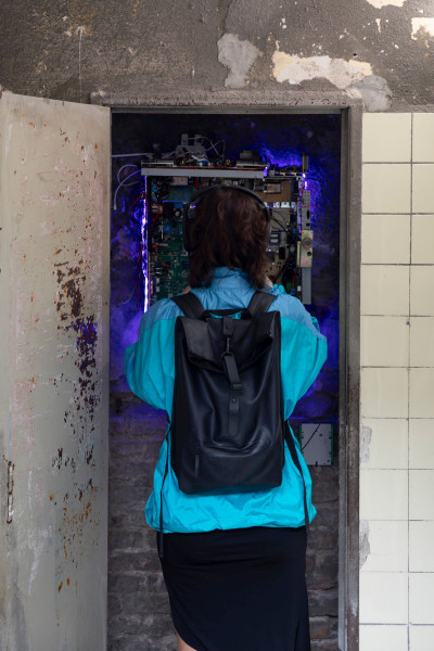 Galeriebesucherin mit Rucksack schaut sich eine Installation an