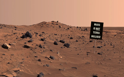 A sign stands on a barren landscape. 