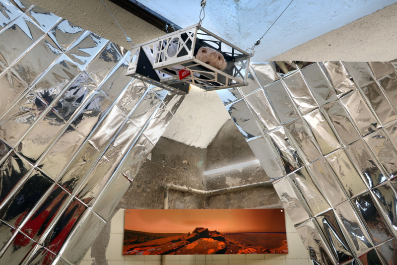 Ein Sonnensegel aus Rettungsdecken und ein Sattelit hängen von der Decke