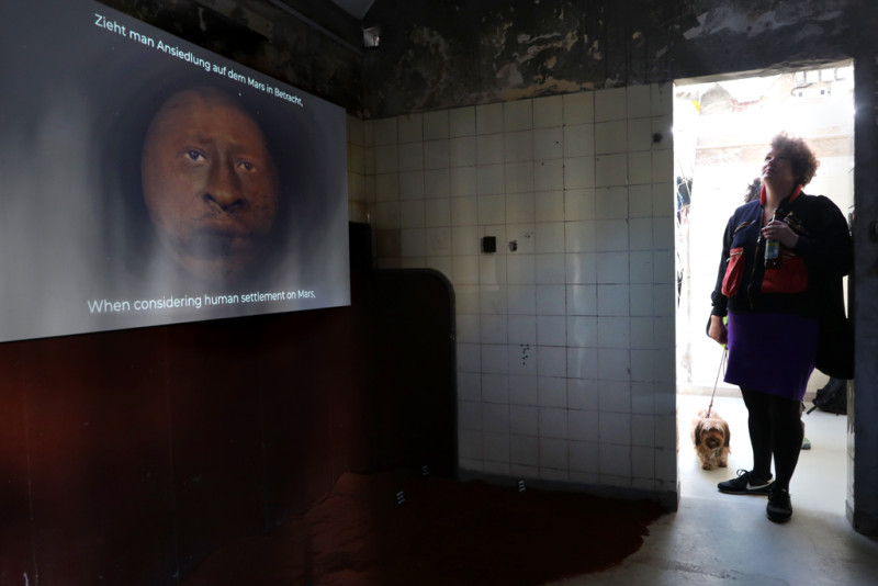 Ein Bildschirm zeigt den Mars und ein Gesicht darauf.