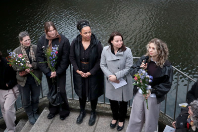 Fünf Frauen stehen mit Blumensträußen an einem Geländer neben einem Gewässer während der Vernissage