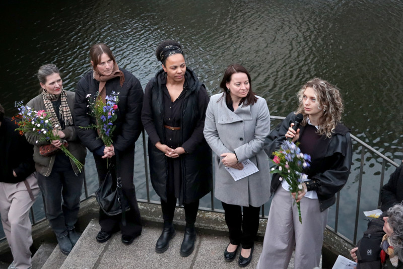 text: >
  Fünf Frauen stehen mit Blumensträußen
  an einem Geländer neben einem Gewässer
  während der Vernissage
decorative: false
source: reviewed