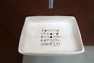 Ein Kunstwerk das einem Waschbecken ähnelt mit dem eingravierten Satz 