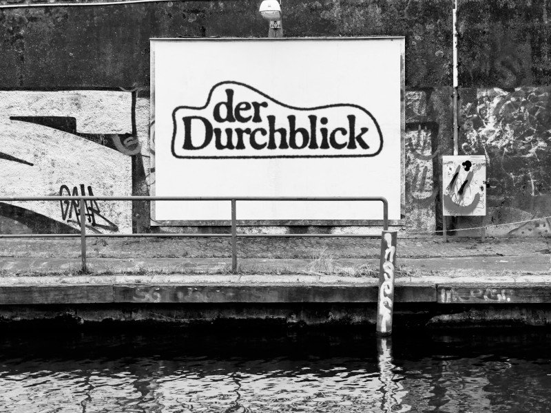 Ein schwarz-weiß Bild der Plakatwand an der Kunstbrücke am Wildenbruch mit dem Text 