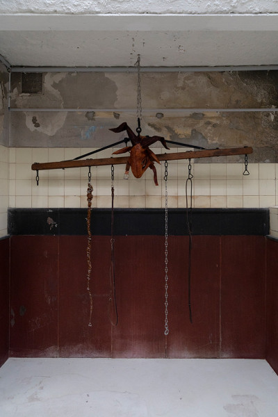 Wooden beam suspended from ceiling with chains and a leather mask of a goat