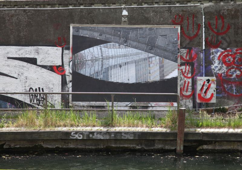 Blick auf ein Plakat: Blick auf eine Wasserspiegelung unter einer Brücke