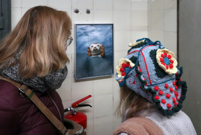 Zwei Frauen betrachten ein Foto eines Porzellanhundes im Wasser in einer Kunstausstellung
