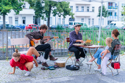 The artists dance, play guitar and interact with the visitors.