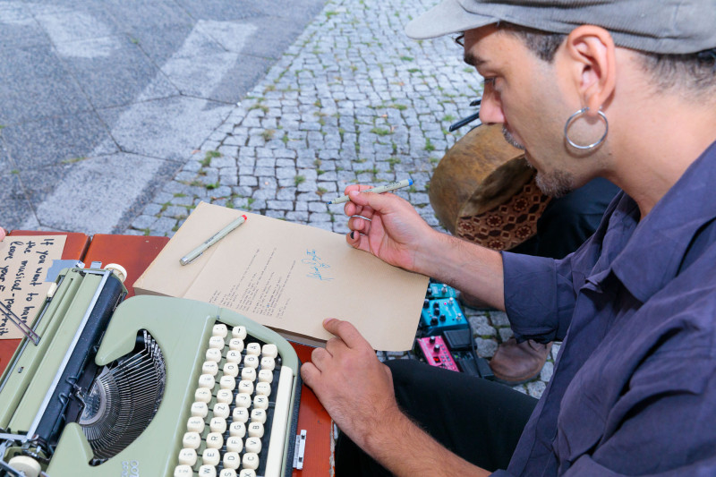 Der Künstler unterschreibt in seiner Performance Briefe.